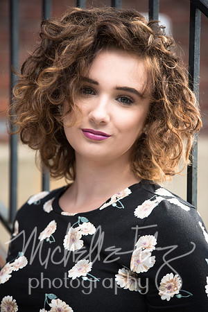Outdoor urban on-location photograph of a brunette high school senior girl with curly hair