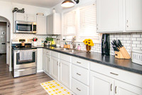 Kitchen with white cabinets, black counter tops, and laminate flooring.